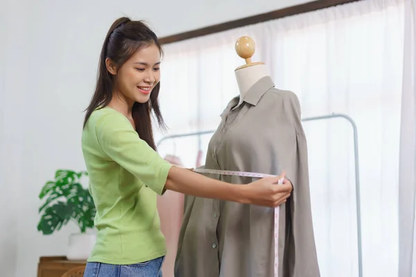 Fashion clothes merchant concept, Female seller present new dress and measure chest size of shirt.
