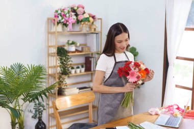 Çiçekçi konsepti. Çiçek buketi yapmak için elinde renkli Gerbera tutan kadın çiçekçi..