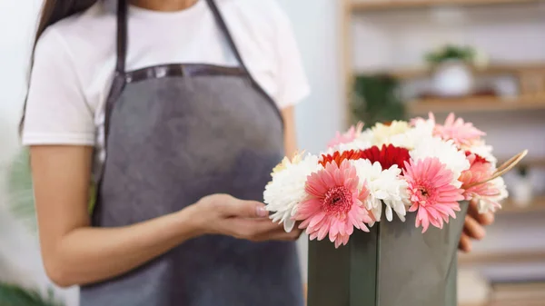 Flower shop concept, Female florist making chrysanthemum and gerbera flower bouquet in shopping bag.