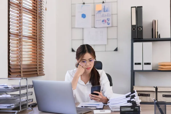 Business concept, Businesswoman reading business data on smartphone while sitting in modern office.