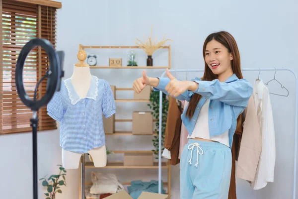 Online marketing concept, Young Asian women thumbs up while recommend clothes in streaming video.