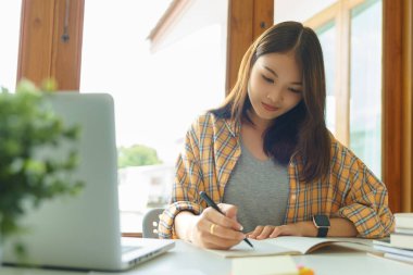Eğitim ve okur yazarlık kavramı, üniversiteli kız dizüstü bilgisayar kullanıyor ve kütüphanede ödev yapıyor..