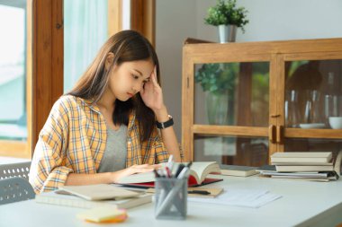 Education and literacy concept, College student girl feel confused while reading a book in library.