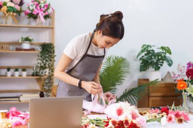 Çiçekçi konsepti, kadın çiçekçi kağıt ve kurdele ile renkli çiçek buketi yapıyor..