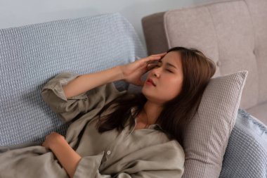 Gitar ve şarkıcı konsepti, baş ağrısı çeken ve müzik öğrendikten sonra kanepeye uzanan genç bir kadın..