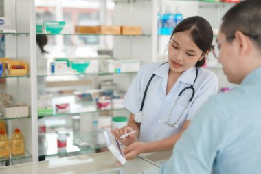Medicine and health concept, Female pharmacist explains medicinal properties to client in drugstore.