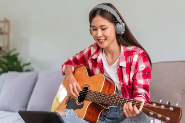 吉他和歌手的概念 年轻的亚洲女人一边在平板电脑上学习音乐一边弹吉他 — 图库照片