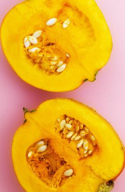 Pembe arka planda iki taze balkabağı uzanır.