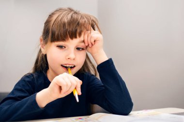Güzel küçük bir kız, ikinci sınıf bir öğrenci. Kitaplar ve defterlerle dolu bir masada oturmak. Savaş ve karantina süresince uzaktan öğrenme