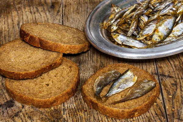 Roggebrood met heerlijke ansjovis op oude houten tafel — Stockfoto