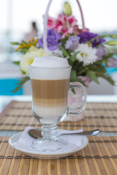 Latte in a glass with a blurred background of a beautiful bouque — Stock Photo, Image