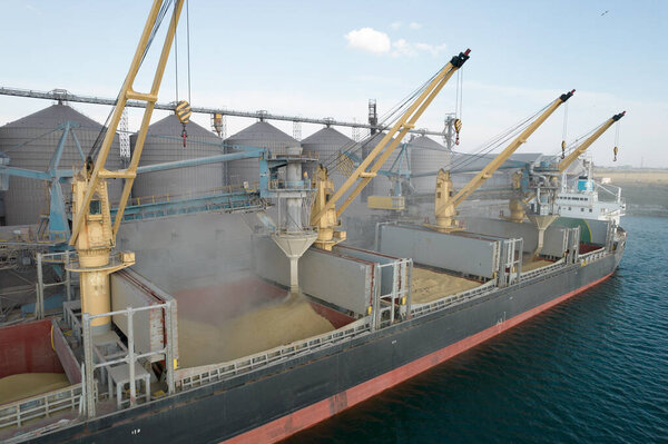 Loading grain into holds of sea cargo vessel through an automatic line in seaport from silos of grain storage. Bunkering of dry cargo ship with grain