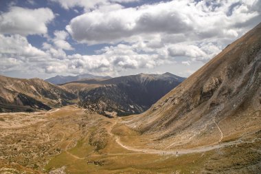 Bastiments zirvesine yakın Pireneler 'de yüksek bir dağın önünde yürüyen insanlar.