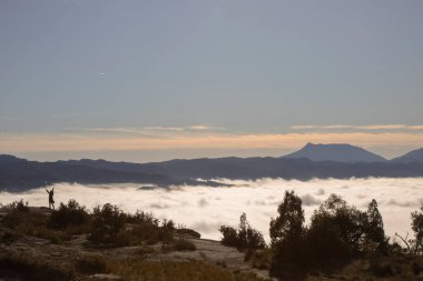Manzara, Katalonya 'nın Tavertet kasabasındaki bir dağın sisli tabakasında bir insanın siluetini gösteriyor.