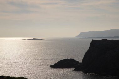 Deniz manzarası, bulutlu bir gökyüzünün altındaki kayalık sahili akşam vakti Costa Brava, Costa Brava 'da Cap de Creus Burnu' nda gösteriyor.