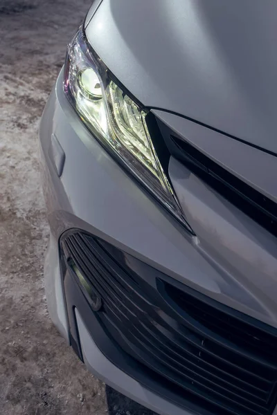 LED far ve modern beyaz arabanın ön tamponunun detaylı görüntüsünü kapat. Yeni otomobilin dış detayları. Akşam sokak otoparkında çekilen kış fotoğrafı.
