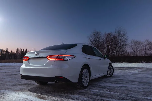 Yeni iş arabası 2021 Toyota Camry XV70 kış gecesi otoparkında. Kırmızı LED ışıkları olan modern arabanın arka tarafında.