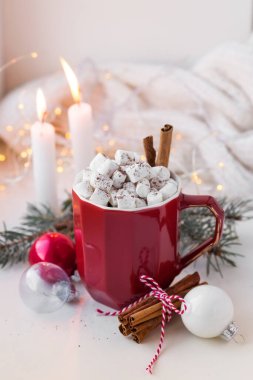 Tarçın çubukları, Noel ağacı dalları ve Noel toplarıyla süslenmiş kakaolu kırmızı bardak ve marşmelov. Kış içeceği