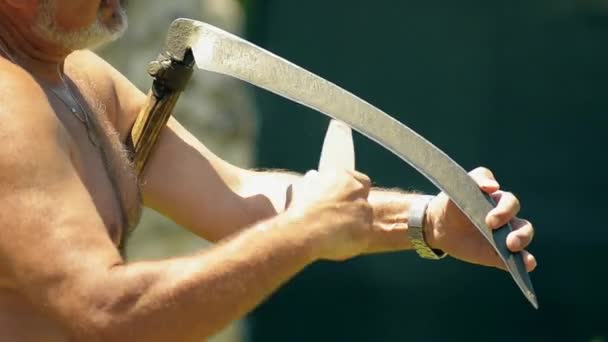 Sharpening scythe in hot summer day — Stock Video