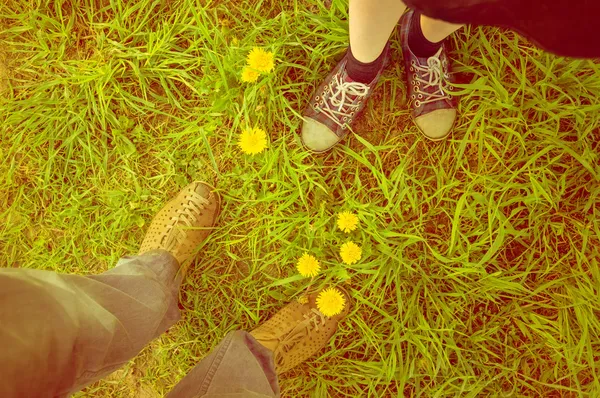 Background met a guy and a girl. Feet in the field — Stock Photo, Image