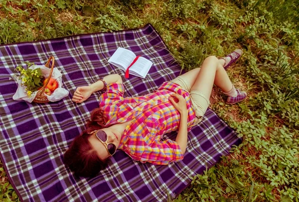 Fundo menina deitado no xadrez na grama no verão para ela ful — Fotografia de Stock