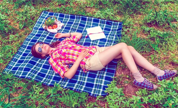 Background girl lying on plaid on the grass in summer to her ful — Stock Photo, Image