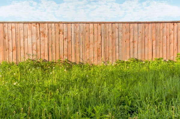 Achtergrond rustieke houten hek met groen gras voor het — Stockfoto