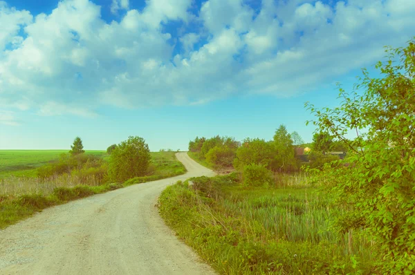 Paisagem estrada país que atravessa o campo . — Fotografia de Stock