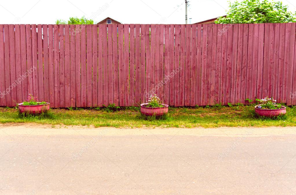 Background rustic wooden fence with flowers in vases and road — Stock