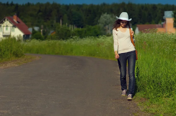 Pozadí dívka jde přímo po cestě krajinou v cowboy ha — Stock fotografie