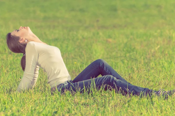 Background girl sitting  on green grass arching her back and eye — Stock Photo, Image