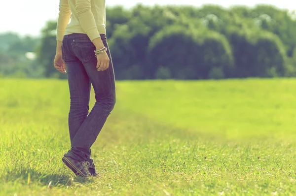 Background girl standing half-turned her back on the park lawn a — Stock Photo, Image