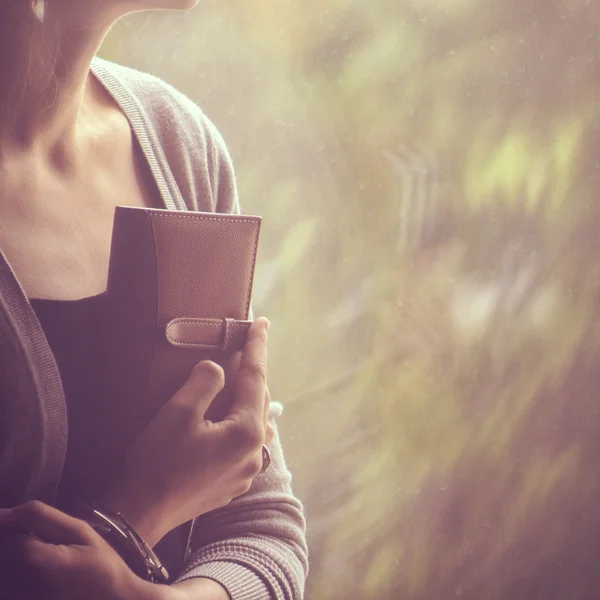 Chica de fondo sentado y mirando por la ventana y sosteniendo una — Foto de Stock