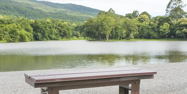 Brown wooden bench at a green lake — Stock Photo, Image