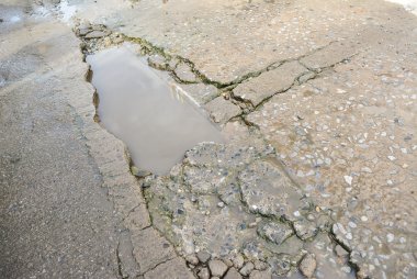 Beton yüzeyi, yol üzerinde yoksul inşaat nedeniyle yıkıldı.