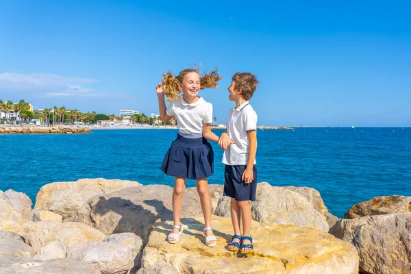 男の子と女の子は海の近くの岩の上をジャンプします 学校の活動の後 高品質の写真 — ストック写真