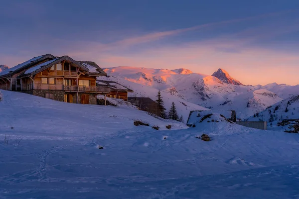 Alpe dHuez, France - 30.12.2021 : Alpine mountain winter resort with wooden chalet on the later evening. Typical french winter season landscape. — Stockfoto