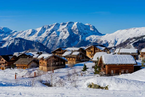Alpe dHuez, Frankreich - 31.12.2021: Winterlandschaft mit Holzchalet im französischen Skigebiet. Fabelhafter Winterblick auf die Berge der Alpen. Hintergrund des Urlaubskonzepts. — Stockfoto