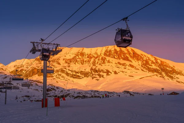 Alpe dHuez, Frankrijk - 30.12.2021: Winterlandschap op alpine bergen resort in de avond. Skiërs op de skipiste. — Stockfoto