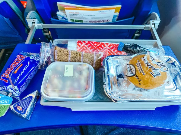 Moscow, Russia - 08.10.2021: Passengers meal in Aeroflot airplane during the flight. Hot lunch on the blue seat table. — Stock Photo, Image