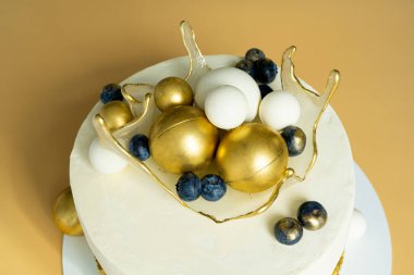 Üzerinde karamelleştirilmiş şeffaf sepet olan altın ve beyaz renklerle süslenmiş güzel bir doğum günü pastası. Festival tatlısı konsepti.