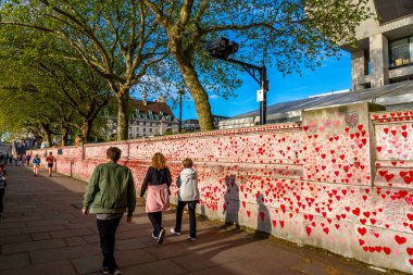 Westminster, Londra İngiltere - 20.04.2022: Covid kurbanlarının ölüm tarihleri ve isimleri ile kırmızı kalplerle boyanmış Ulusal COVID Anıt Duvarı.