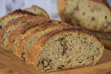freshly made sourdough bread with walnuts cut into slices on a board - macro