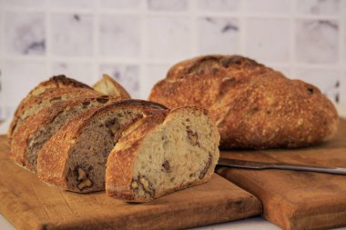 freshly made sourdough bread with walnuts cut into slices on a board