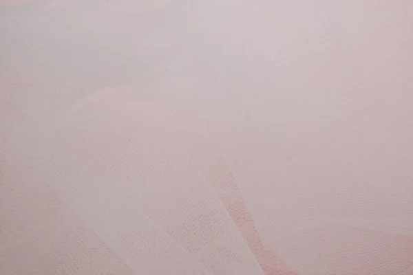 Delicado tecido branco arejado com dobras em um fundo rosa — Fotografia de Stock