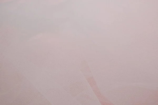 Pembe arka planda kıvrımları olan yumuşak, beyaz bir kumaş.