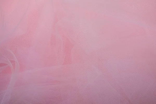 Delicado tecido branco arejado com dobras em um fundo rosa — Fotografia de Stock