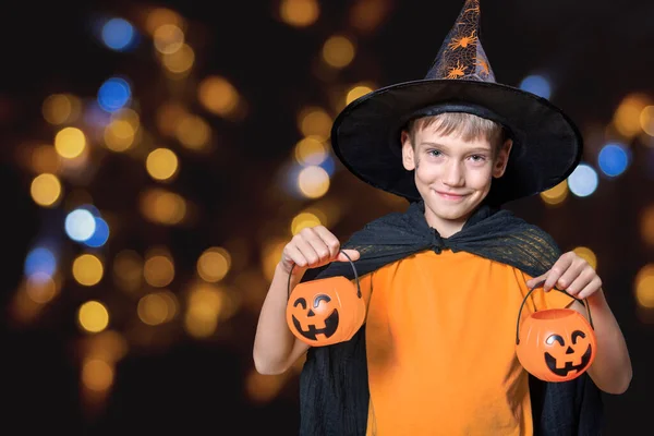 Les enfants Halloween. Garçon en chapeau de sorcier et t-shirt orange tenant Halloween seaux en forme de citrouille de bonbons — Photo