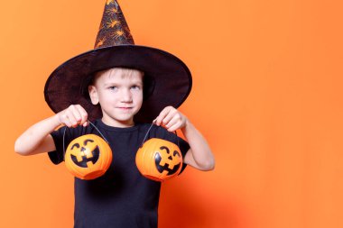 Mutlu Cadılar Bayramı. Korkunç cadılar bayramı çocukları. Kafasının önünde cadılar bayramı balkabağı tutan şapkalı bir çocuk.