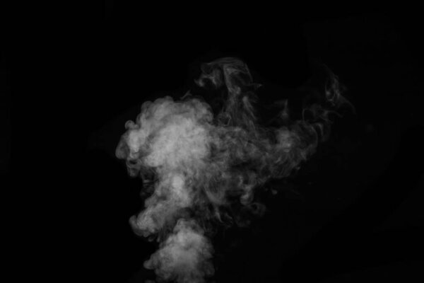 Fragment of white hot curly steam smoke isolated on a black background, close-up. Create mystical Halloween photos. Abstract background, design element